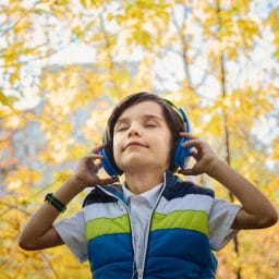 Boy with headphones on with trees in the background
