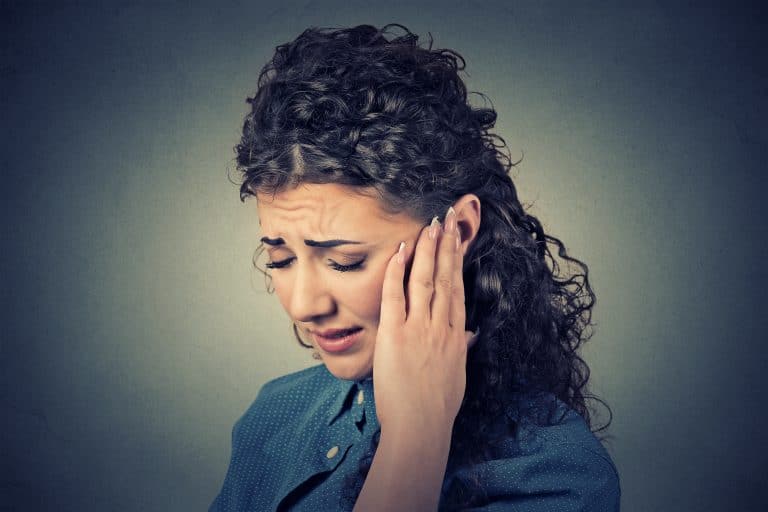 An adult holding an ear in pain
