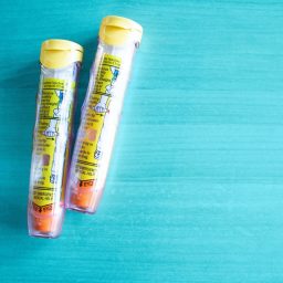 Picture of two EpiPens behind a teal background.