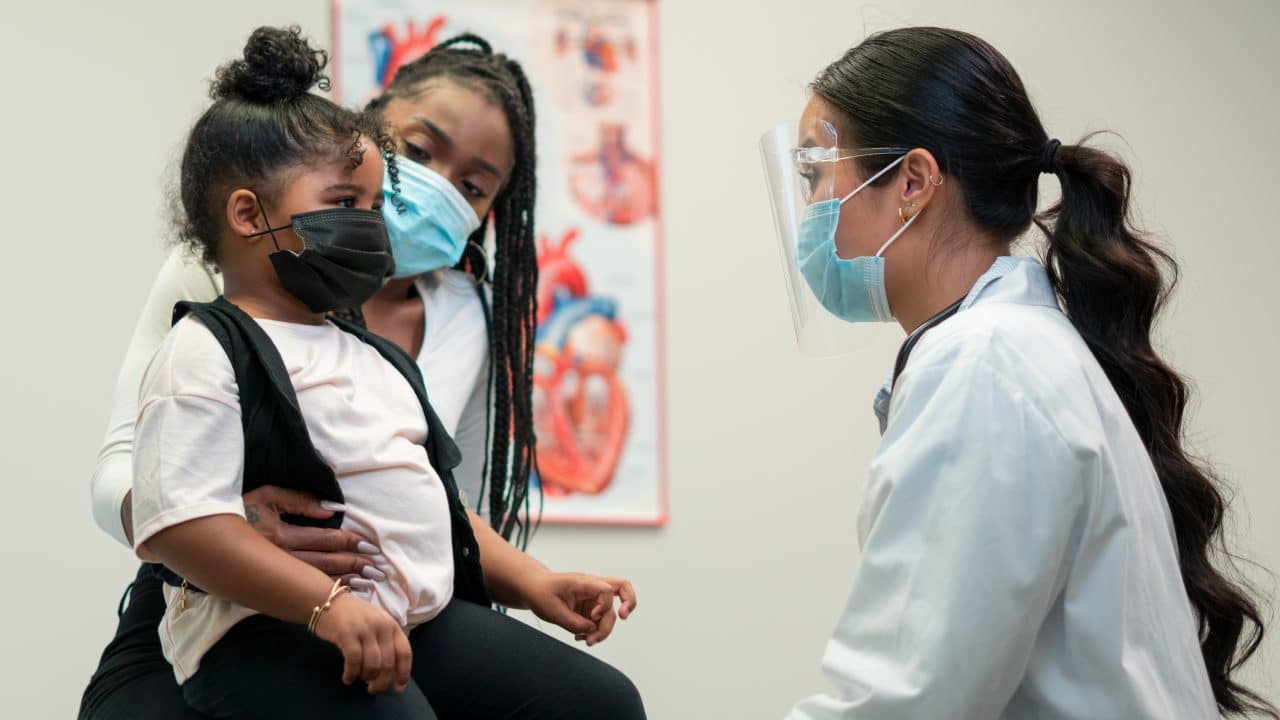Mother and daughter talk to a pediatric doctor.