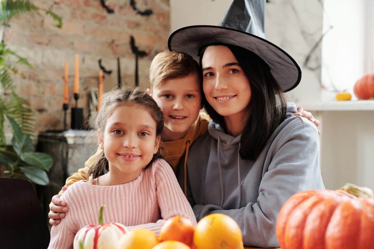 Mother in a witch costume poses with her two kids for Halloween.