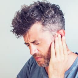 Man with tinnitus putting his hand to his ear.