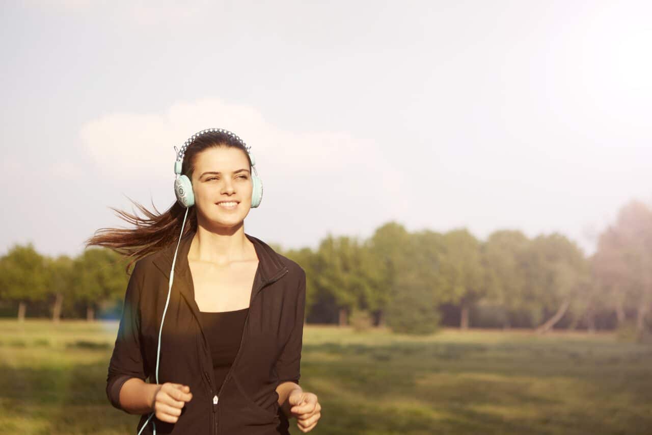 Young woman with headphones jogging outside.