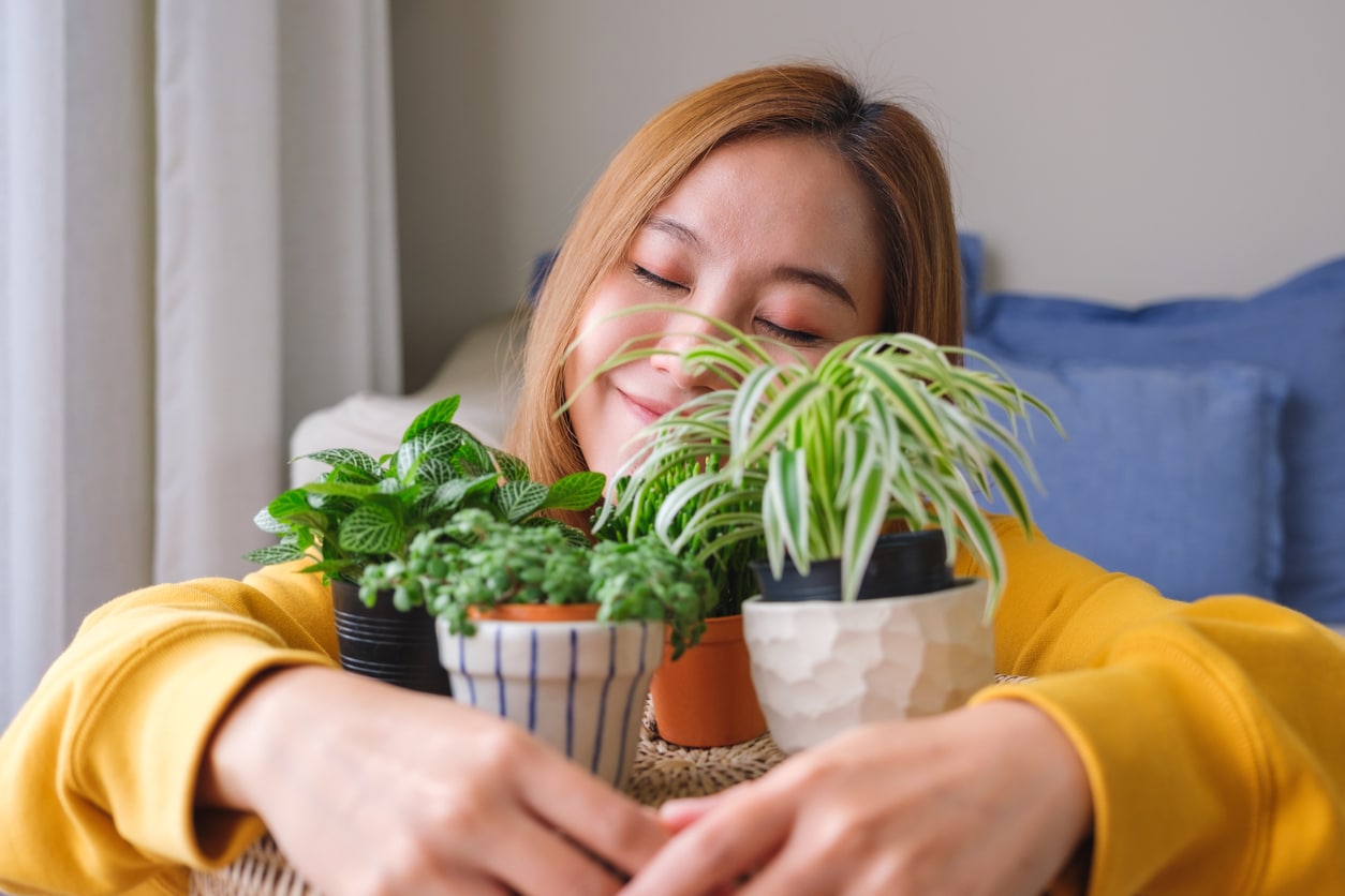 Happy woman holding onto a couple of small house plants.