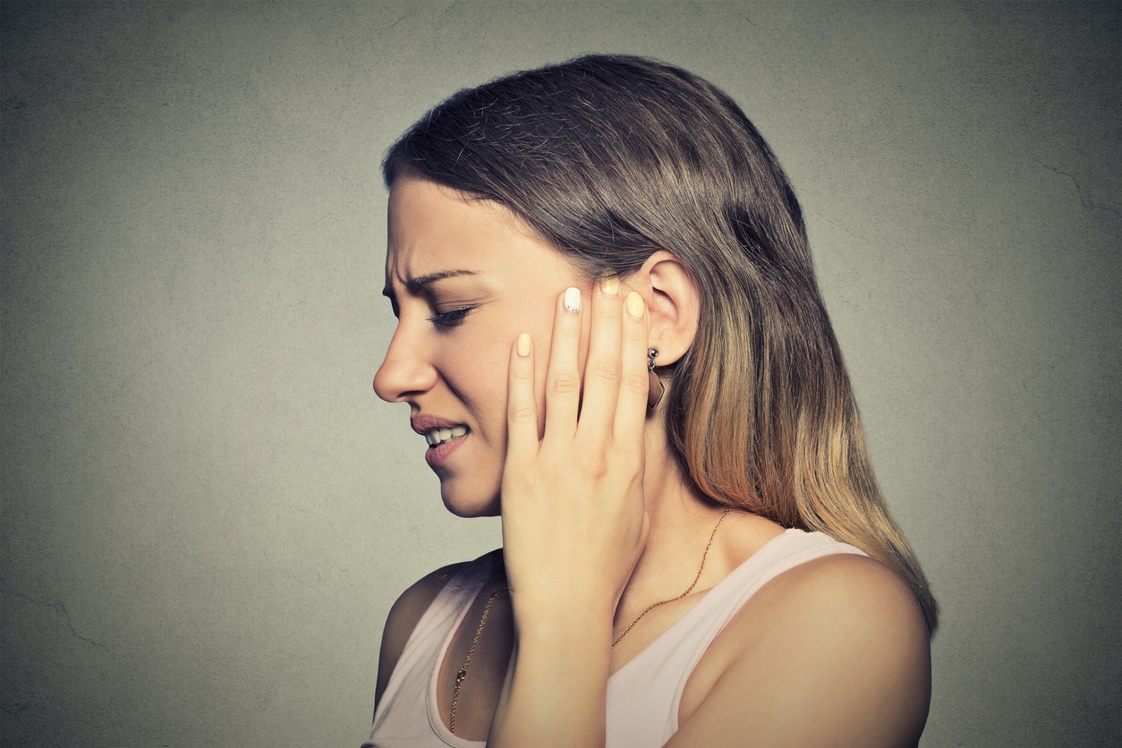 Woman holds ear in pain