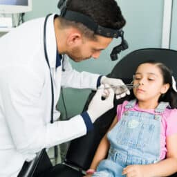 ENT doctor removing an object from a young girl's nose