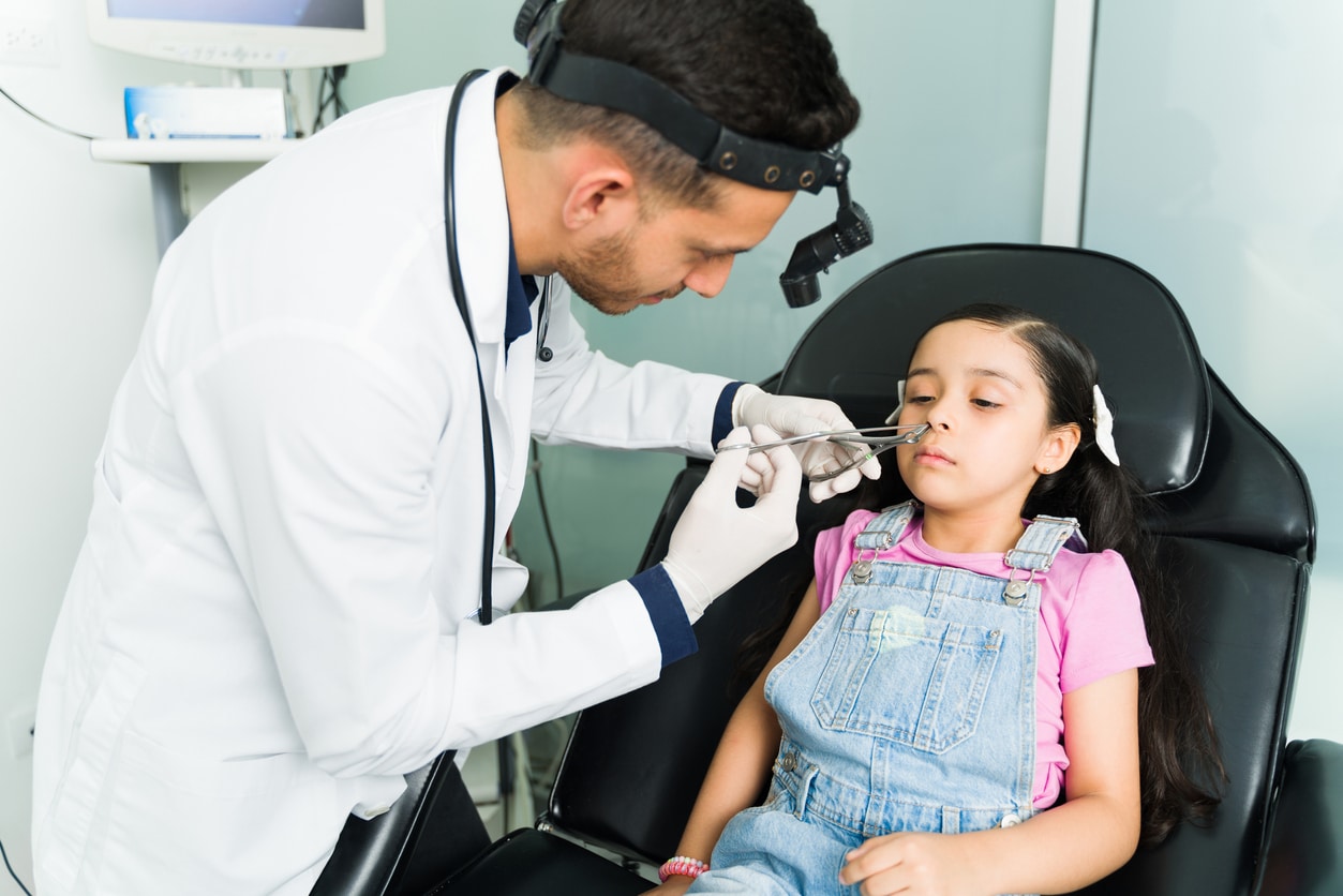 ENT doctor removing an object from a young girl's nose.