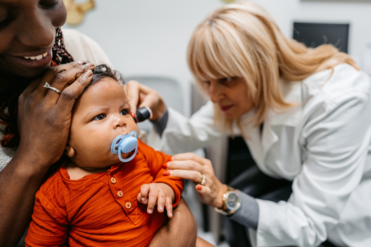 Baby gets ear examined by doctor