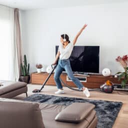 Happy woman vacuuming her home.